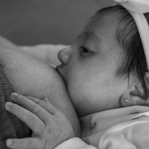 mother breastfeeding newborn baby girl during follow-up lactation consult